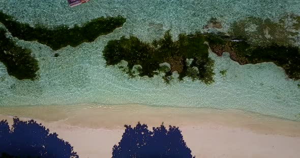 Daytime drone tourism shot of a white paradise beach and blue ocean background in high resolution 4K