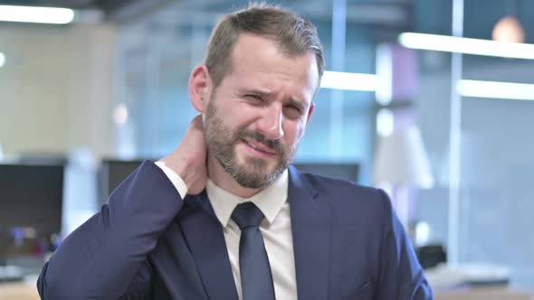 Portrait of Tired Businessman Having Neck Pain in Office