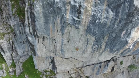 Aerial drone view of a man rock climbing up a mountain.