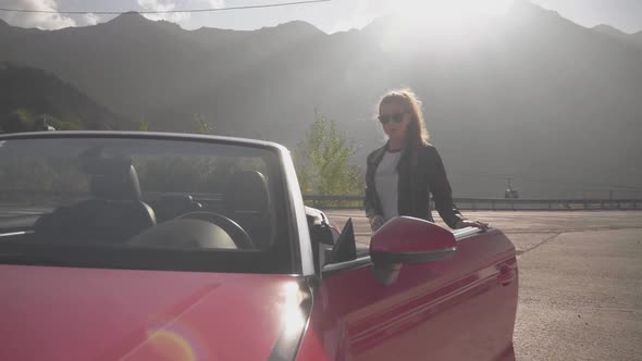 Girl Gets Into Red Cabriolet at Mountains. Summer Vacation Mood.