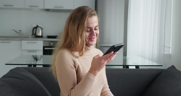 Blonde Woman Sitting in Couch Make Recording Voice with Smartphone at Home