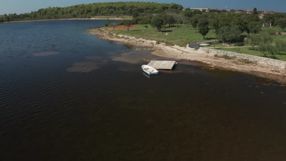 Aerial shot of a small white rowboat at a collapsed small peer. Peer collapsed due to flood.