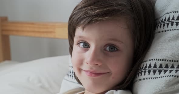 Portrait Cute Little Boy with Blue Eyes Brunette Hair Lying on Comfortable Pillow Relaxing at Home