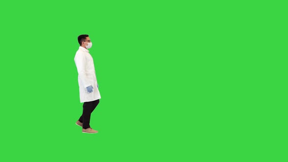 Young Male Doctor in Mask Looking at His Wristwatch and Runs Being Late on a Green Screen Chroma Key