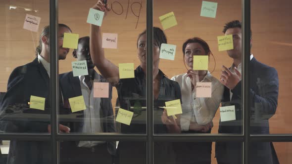 Business Meeting, International Management Team at Work, Team Is Standing Next To a Glass Board 