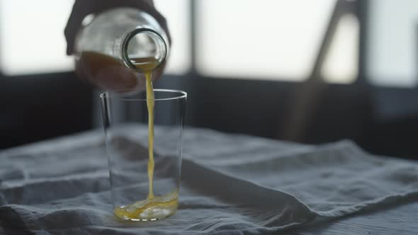Slow Motion Pour Orange Juice Into Tumbler Glass on Linen Cloth