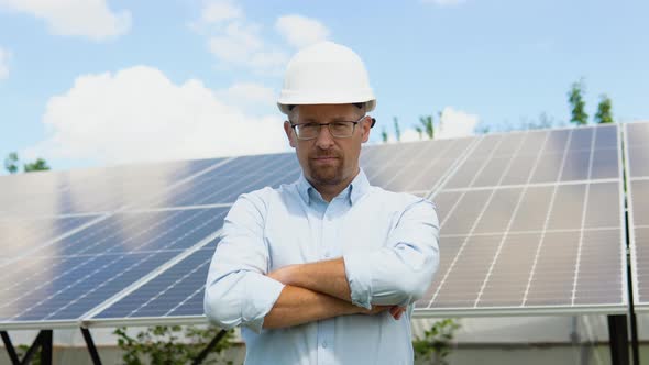 Close Up Portrait of Male Worker in Protective Helmet Standing Near Solar Panel