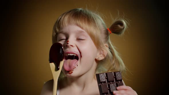 Joyful Smiling Child Kid Girl with Dirty Face From Melted Chocolate on Dark Background in Studio