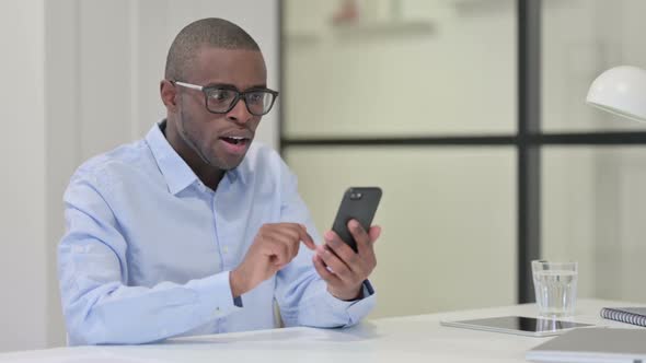 African Man Celebrating While Using Smartphone