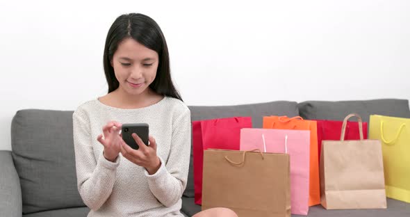 Woman Using Mobile Phone for Online Shopping with Lots of Paper Bag at Home