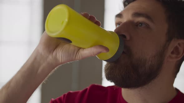 Bearded Man Drinking Water While Resting After Home Exercise Routine