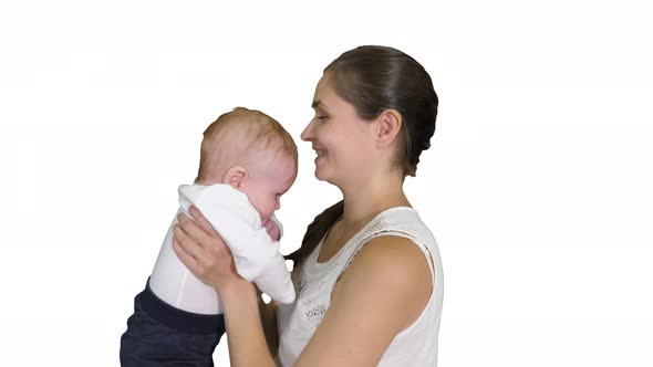 Positive Little Cute Boy with Beautiful Mom Rising Her Baby Up on White Background.