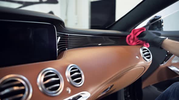 Side View of Man Taking Care of Car Interior in Garage. Cleaning Dashboard with a Microfiber.