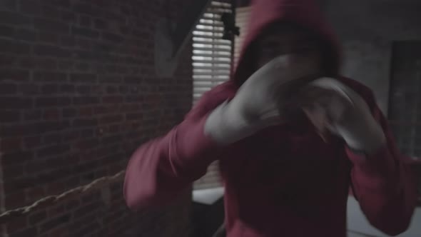 African Boxer in Hooded Sweatshirt Practicing Punches at Fight Club