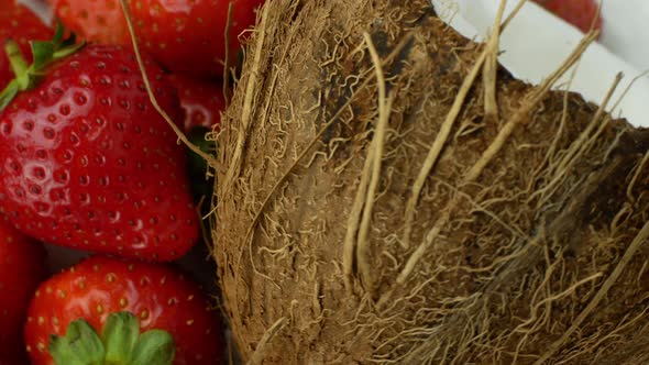 Tropical fruits coconut and strawberry rotate on a white background. Slow spinning exotic