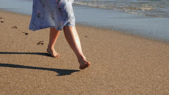 Female feet walking barefoot on sandy beach