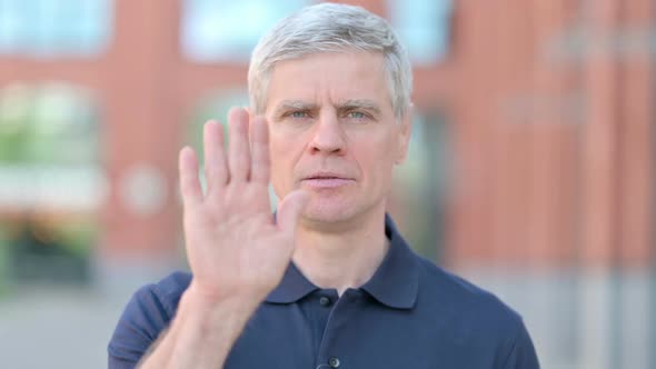 Outdoor Portrait of Middle Aged Man Saying No with Head and Hand Sign