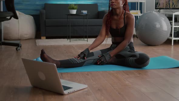 Woman with Dark Skin Doing Pilates Workout in Living Room Stretching Body Muscles