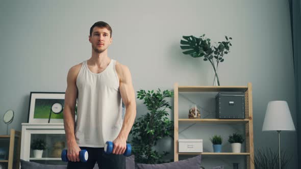 Handsome Guy Exercising with Dumb-bells at Home Lifting Weight Training Muscles