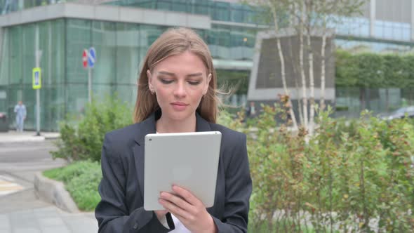 Attractive Young Businesswoman Using Tablet While Walking on the Street