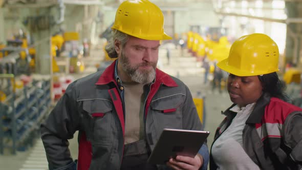 Diverse Factory Workers Using Digital Tablet and Talking