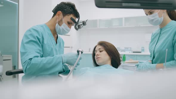 Dentist with Nurse and Patient in Dentist Office. A Patient Getting Dental Treatment at Dental