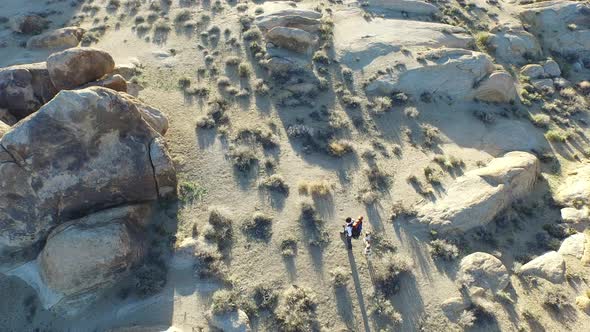 Aerial shot of a young man backpacking with his dog in a mountainous desert.