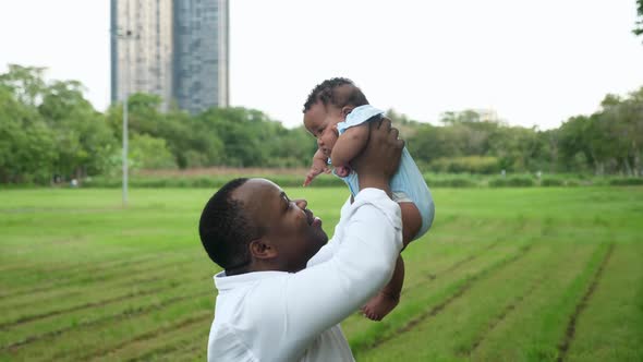 African father holding his newborn female child up in the sky, and kissing her