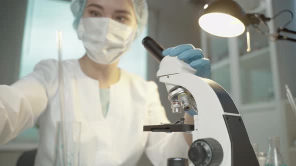 Female Doctor In Laboratory With Microscope And Chemical Test Tubes