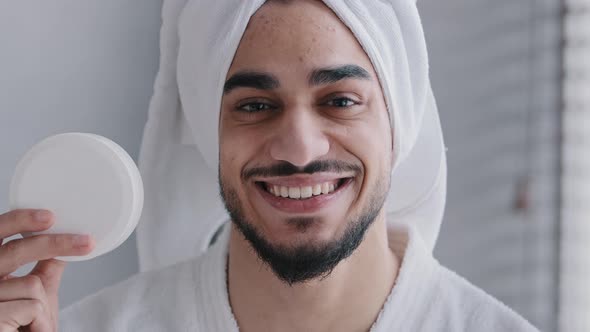 Arabian Hispanic Indian Man with Towel on Head Holding Jar of Cream for Face Laugh Looking at Camera