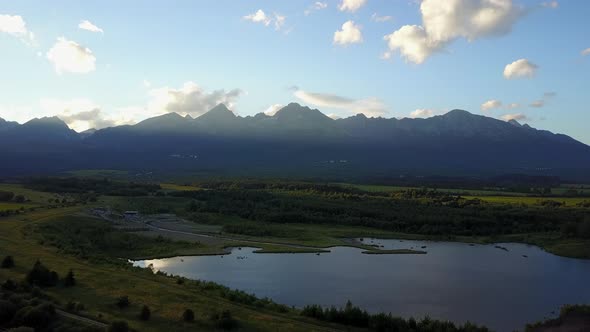 Drone aerial view of The High Tatras Mountain Range in Poprad, Slovakia, sunset golden hour. Wide sh