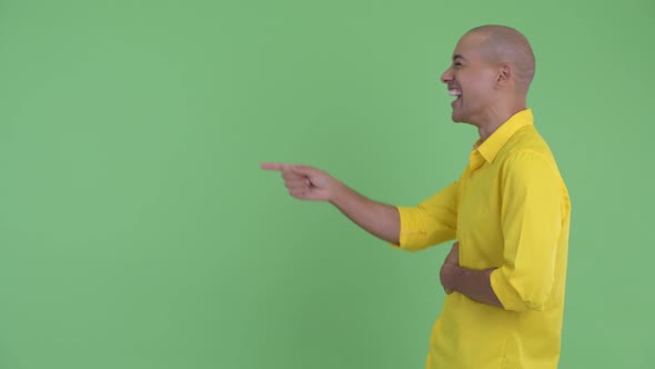 Profile View of Happy Handsome Bald Businessman Laughing and Pointing Finger