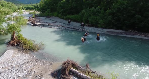 People on Horseback Cross a Mountain River  Drone Shot