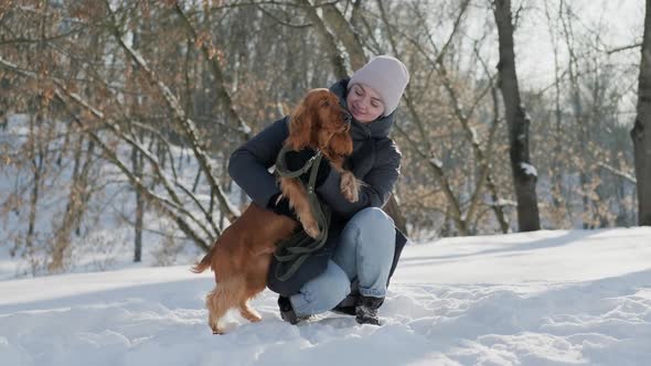 Young Woman Sitting Face to Face Playing with Her Spaniel Dog in Winter Park