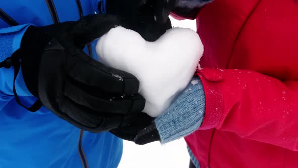 Mid section of couple making snow heart