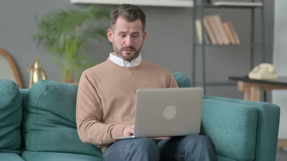 Man with Laptop Having Headache on Sofa