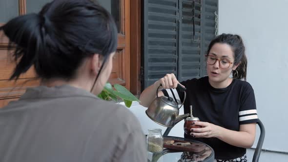 Beautiful young woman smiling, chatting with her friend and sharing a Mate, a local beverage of Arge