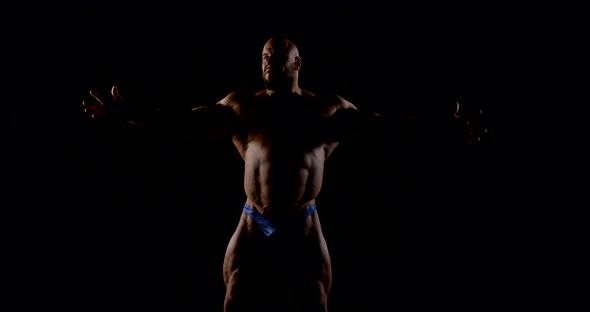 Brutal Muscular Bald Bearded Male Bodybuilder Close-up on a Black Background, He Poses, Shows