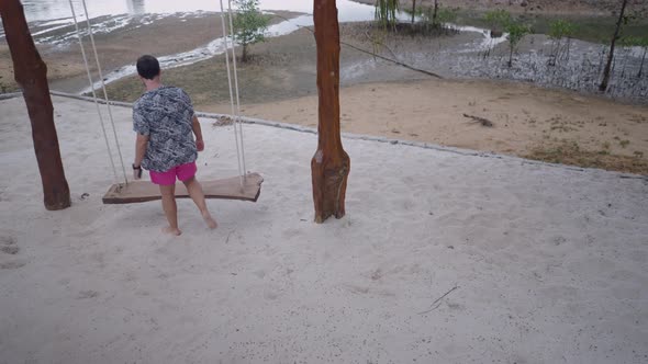 Man Come Up and Sit on Wooden Beach Swing Enjoy Swinging in Thailand Island Village