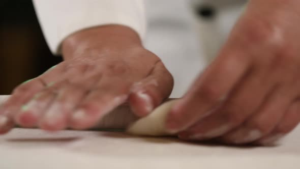 Hand rolling Chinese dumplings with a wooden rolling pin - side view