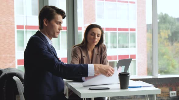 Man and woman work in comfortable modern office sitting at the table. Working process. 