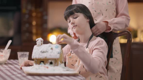 Girl Decorating Ginger House with Unrecognizable Woman Touching Hair