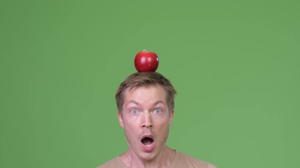 Close Up Shot of Young Handsome Scandinavian Man with Apple on Head