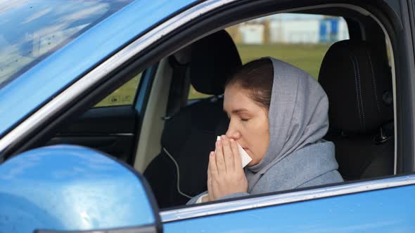 Woman Sneezes and Blows Nose in Paper Napkin Sitting in Car