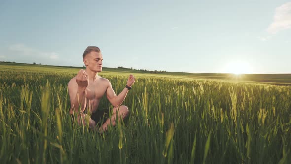 A Man is Sitting in the Middle of a Field and Meditating