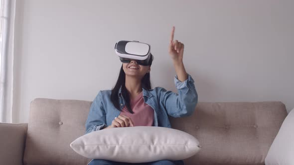 Attractive portrait young Asian woman wearing VR headset in the living room playing a game.