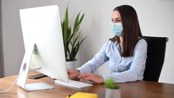 A Female in Mask Using PC in the Office