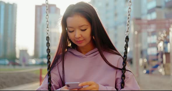 Asian Woman in Sportswear Using Smartphone Outdoors