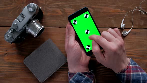 Photographer Using Smartphone  with Green Screen on Wood Table