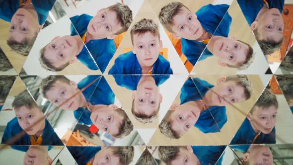 Curious boy in blue and yellow shirt reflecting in the mirrors of kaleidoscope.